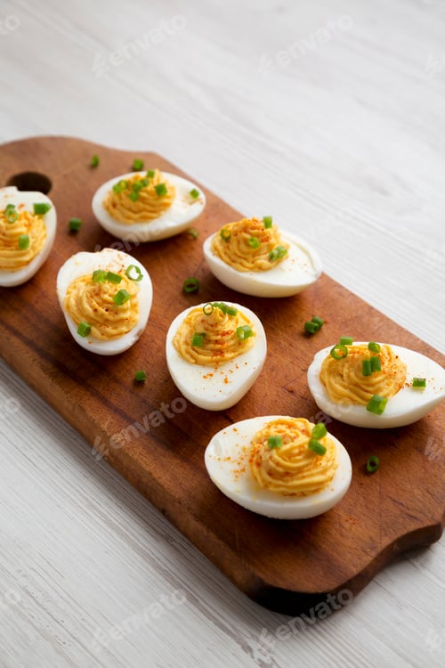 Preview: Homemade Deviled Eggs With Chives On A Rustic Wooden Board On A White Wooden Background, Side View