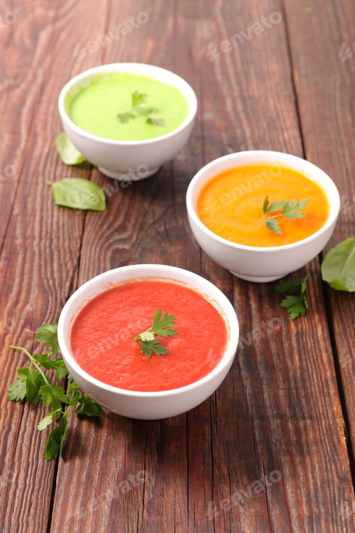 Brightly Colored Soups in White Bowls on Wood