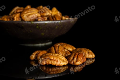 Preview: Lot Of Whole Dry Brown Pecan Nut In Dark Ceramic Bowl Isolated On Black Glass