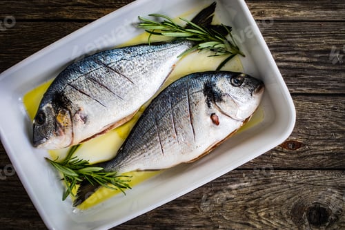 Preview: Fresh Dorada And Herbs In Cooking Pot On Wooden Background