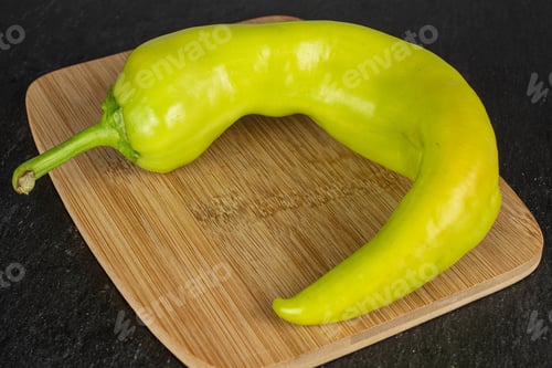 Preview: One Whole Hot Green Pepper Banana On Bamboo Cutting Board On Grey Stone