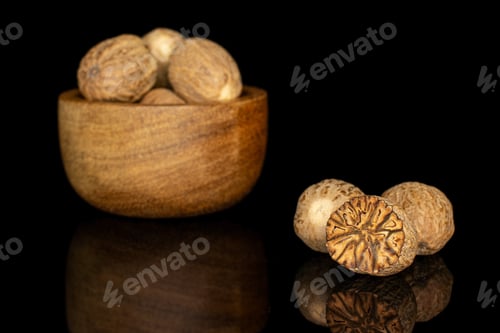 Preview: Group Of Six Whole One Half Of Dry Brown Nutmeg In Tiny Wooden Bowl Isolated On Black Glass
