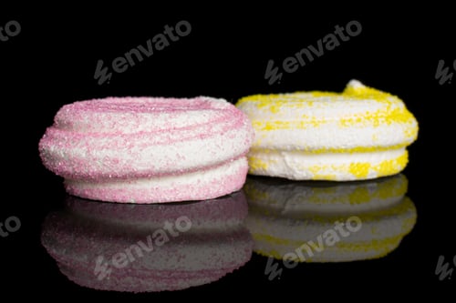 Preview: Group Of Two Whole Pink And Yellow Sweet Meringue Isolated On Black Glass