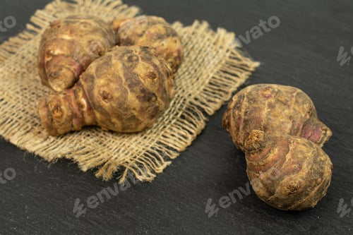 Preview: Group Of Five Whole Fresh Brown Jerusalem Artichoke On Natural Sackcloth On Grey Stone