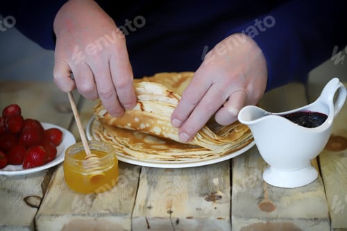 Preview: Selective Focus. Soft Focus. Male Hands Are Wrapping A Pancake On A Plate. Shrovetide Celebration