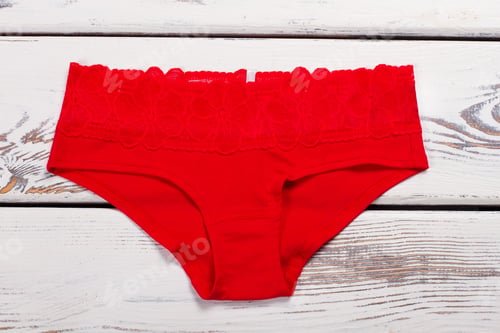 Preview: Red Cotton Underwear On A Wooden Background. Red Pants With Lace On Every Day.