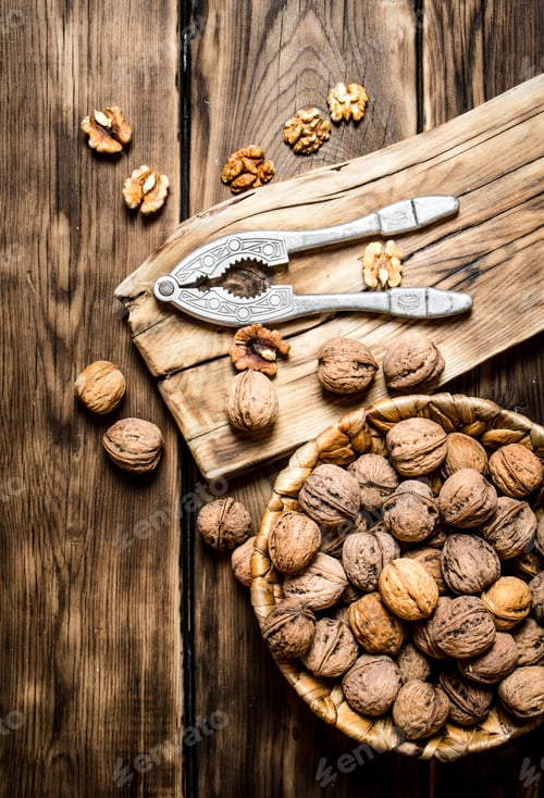 Preview: Walnuts With Nutcracker On The Board. On A Wooden Table.