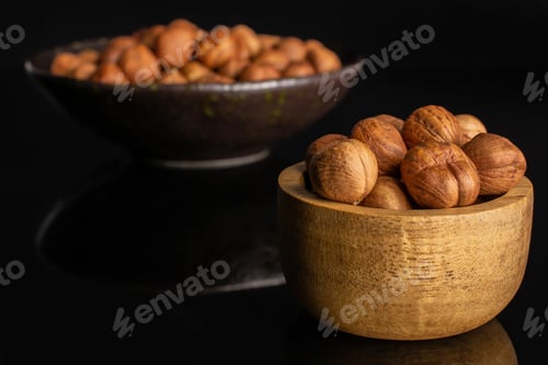 Preview: Lot Of Whole Ripe Brown Hazelnut In Dark Ceramic Bowl In Tiny Wooden Bowl Isolated On Black Glass