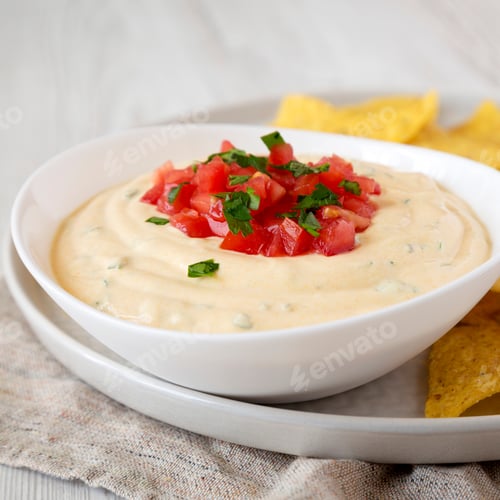 Preview: Homemade Cheesy Dip In A Bowl, Yellow Tortilla Chips, Low Angle View. Close-Up.