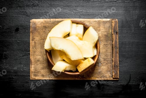 Preview: Sliced Melon In A Wooden Bowl . On The Black Wooden Table.