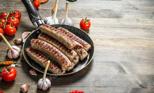 Preview: Fried Sausages In A Frying Pan. On A Wooden Table.