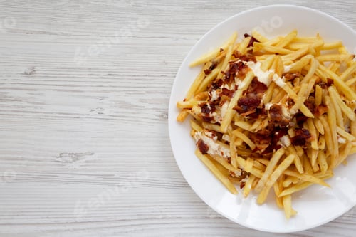 Preview: French Fries With Cheese Sauce And Bacon On A White Plate Over White Wooden Background, Top View