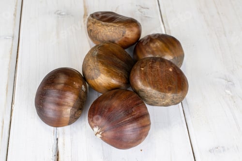 Preview: Group Of Six Whole Edible Brown Chestnut On White Wood