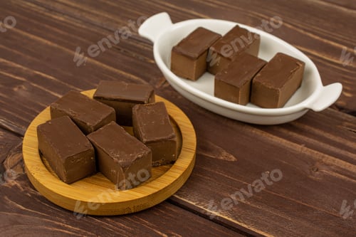 Preview: Group Of Nine Whole Sweet Brown Viennese Nougat In White Oval Ceramic Bowl On Bamboo Coaster On