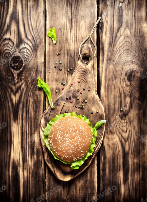 Preview: A Burger On An Old Wooden Board With Spices. On Wooden Background. Top View.