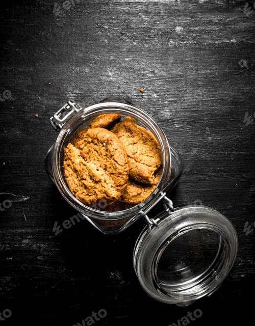Preview: Oatmeal Cookies In A Jar. On A Black Wooden Background.