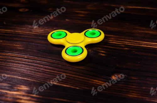 Preview: Yellow Fidget Spinner On Rustic Wooden Desk