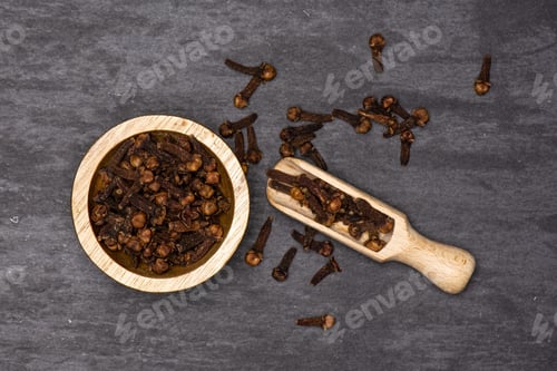 Preview: Lot Of Whole Small Dried Cloves Spice Scoop With Wooden Bowl Flatlay On Grey Stone