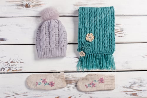 Preview: Winter Handmade Set Of Things. Wool Scarf, Hat And Mittens On A Wooden Background.