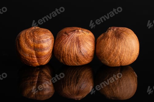 Preview: Group Of Three Whole Ripe Brown Hazelnut In Row In Closeup Isolated On Black Glass