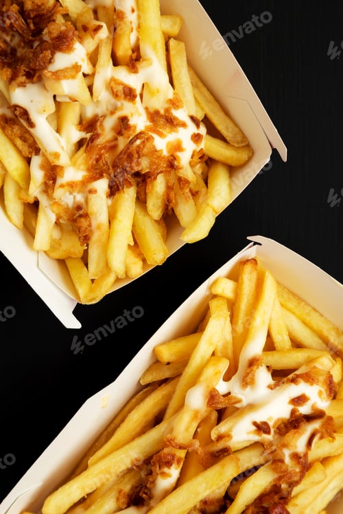 Preview: French Fries With Cheese Sauce And Fried Onion In Paper Boxes On A Black Background, Top View. Flat