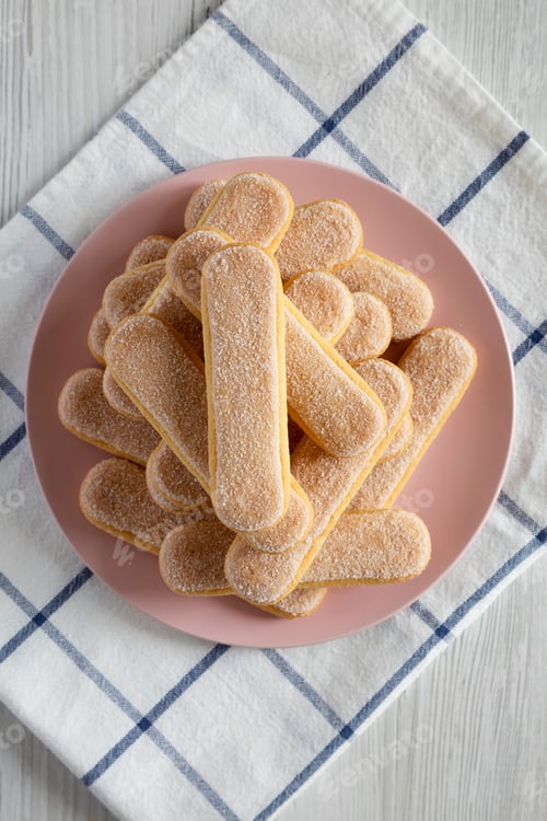 Preview: Savoyardi Biscuits On Pink Plate Over White Wooden Surface, Top View. Flat Lay, Overhead, From