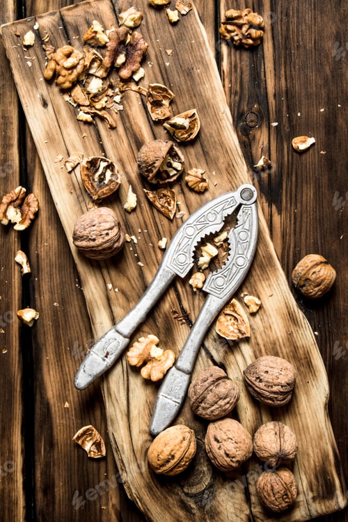 Preview: Walnuts With Nutcracker On The Board. On A Wooden Table.