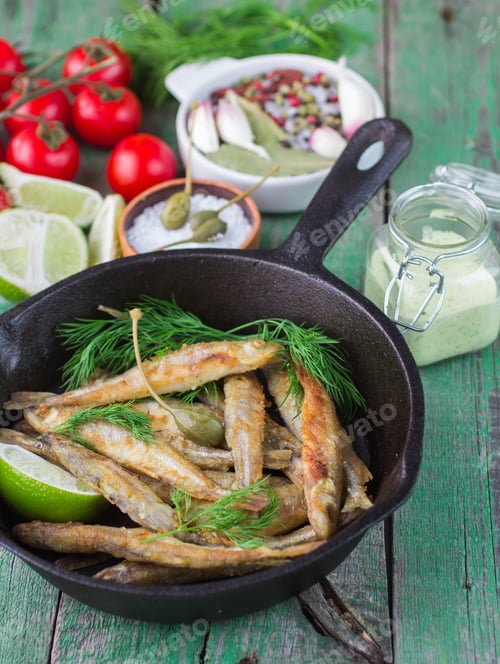 Preview: Fried Small Fish. Fried Smelt In The Pan On The Table With A Sauce, Lime, Tomatoes, Dill And Garlic