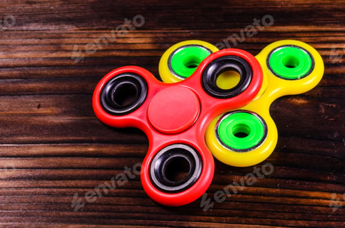Preview: Yellow And Red Fidget Spinners On Rustic Wooden Desk