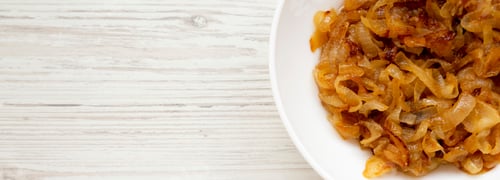 Preview: Homemade Caramelized Onions On A White Plate On A White Wooden Surface. Flat Lay, Overhead, Top