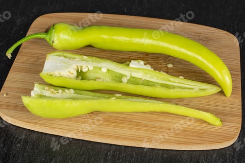 Preview: Group Of One Whole Two Halves Of Hot Green Pepper Banana On Bamboo Cutting Board On Grey Stone