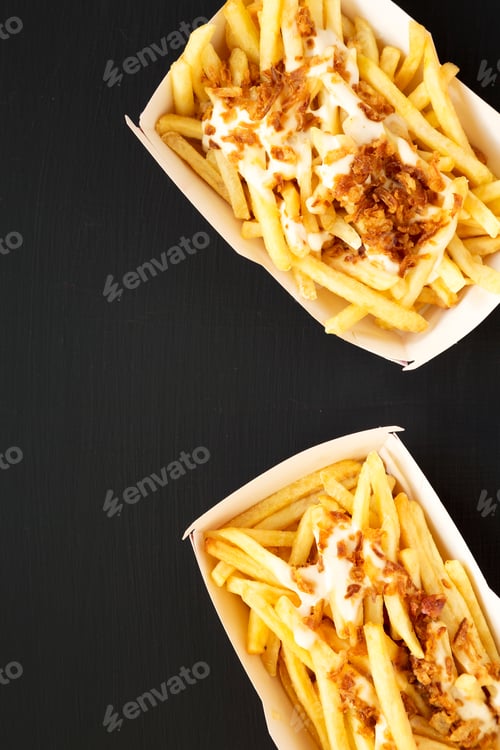 Preview: French Fries With Cheese Sauce And Onion In A Paper Box On A Black Surface, Top View. Flat Lay