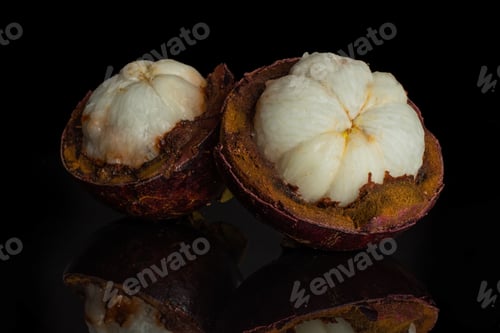 Preview: Group Of Two Halves Of Deep Purple Mangosteen Segmented Flesh Isolated On Black Glass