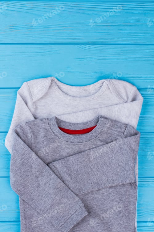 Preview: White And Grey Cotton Baby Creepers. Blue Wood Background.
