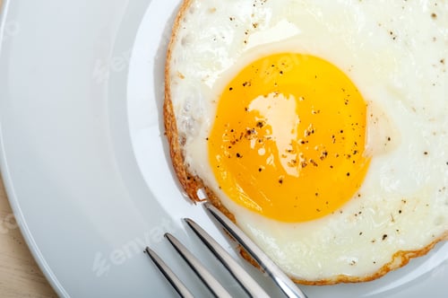 Preview: Fried Egg Sunny Side Up On A Plate With Fork Over Wood Table