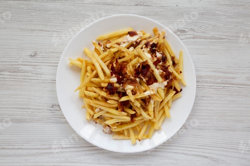 Preview: French Fries With Cheese Sauce And Bacon On A White Plate Over White Wooden Background, Overhead