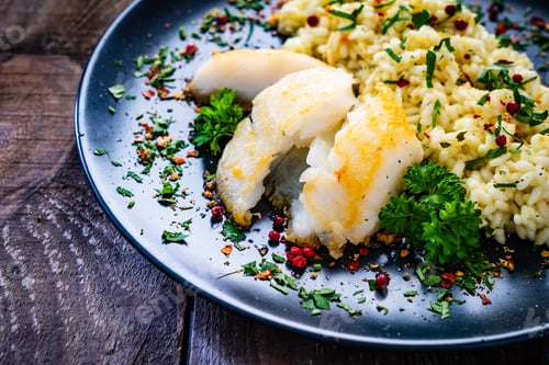 Preview: Risotto With Fried Cod Loin On Wooden Background