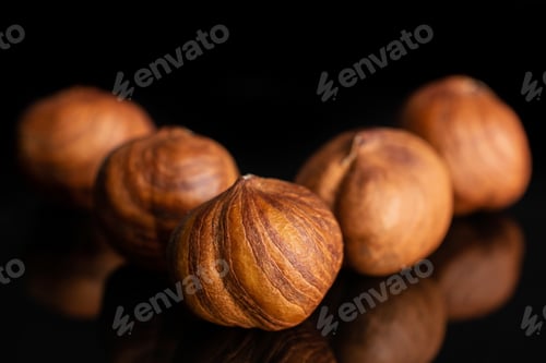 Preview: Group Of Five Whole Ripe Brown Hazelnut Arranged Symmetrically In Closeup Isolated On Black Glass