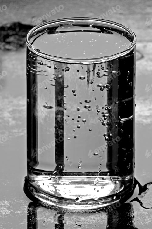 Preview: A Glass Of Clean Drinking Water On A Metallic Wet Surface, In Black And White.