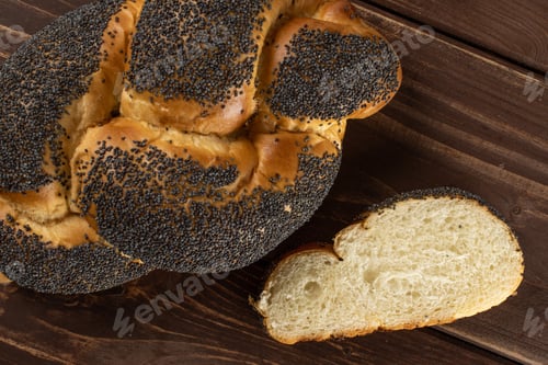 Preview: Group Of One Whole One Slice Of Twisted Poppy Seed Bun Flatlay On Brown Wood