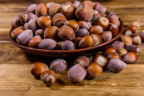 Preview: Plate With Pile Of Hazelnuts On Wooden Table