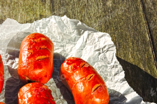 Preview: Appetizing Fried Sausages In Paper On A Wooden Background.