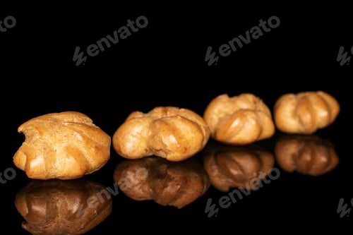 Preview: Group Of Four Whole Baked Golden Profiterole In Row Isolated On Black Glass