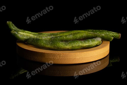 Preview: Group Of Three Whole Dry Vegetable Chip Of Green Bean On Bamboo Coaster Isolated On Black Glass