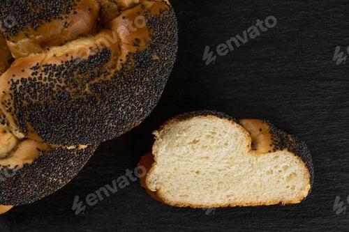 Preview: Closeup Of One Whole One Slice Of Twisted Poppy Seed Bun Flatlay On Grey Stone