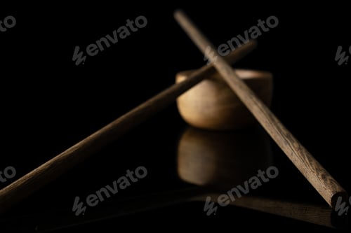 Preview: Group Of Two Whole Dark Asian Brown Chopsticks Crossed With Wooden Bowl Isolated On Black Glass