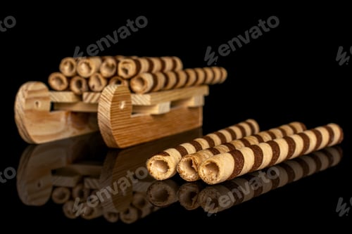 Preview: Lot Of Whole Crunchy Beige Hazelnut Rolled Wafer Biscuit With Wooden Sledge Isolated On Black Glass