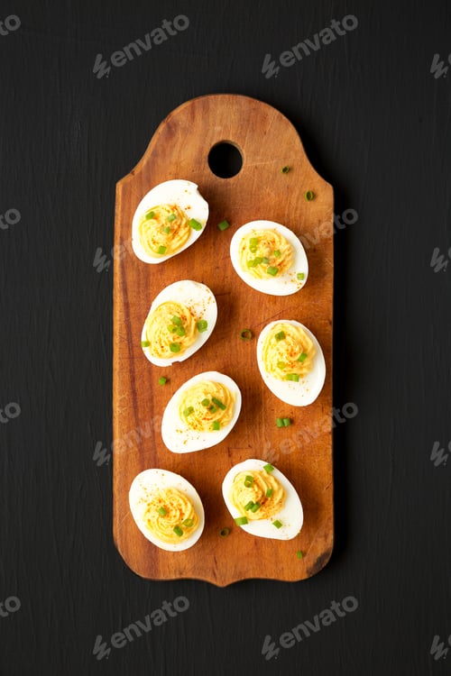 Preview: Homemade Deviled Eggs With Chives On A Rustic Wooden Board On A Black Background, Top View. Flat