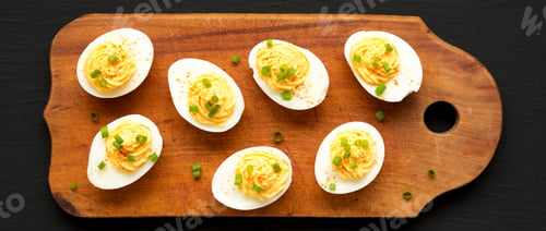 Preview: Homemade Deviled Eggs With Chives On A Rustic Wooden Board On A Black Surface, Top View. Flat Lay