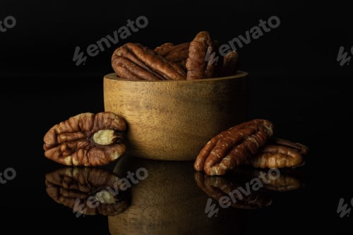 Preview: Lot Of Whole Fresh Brown Pecan Nut Half In A Wooden Bowl Isolated On Black Glass